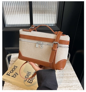 Détail d'un sac en toile et cuir sur une table en marbre à côté d'un livre