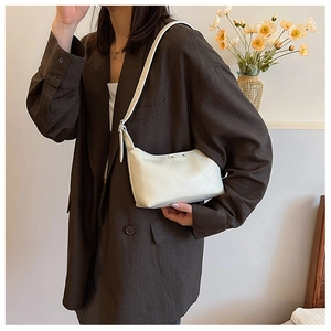 Detail view of white quilted dumpling bag with adjustable strap and diamond stitching