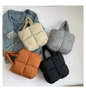 Detailed overhead view of quilted down tote bags in white, grey, orange and black colors