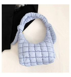Detalle de bolso acolchado azul claro con asa anudada y cremallera dorada