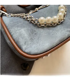 Close-up of gray denim fabric texture with pearl and silver chain detailing