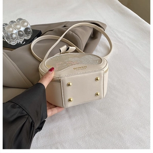 Detail view of cream leather handbag with vintage floral pattern and gold metal feet