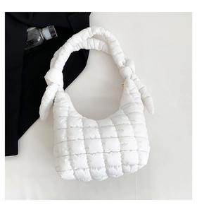 Detalle de bolso acolchado blanco con correa anudada y textura de cuadros suave