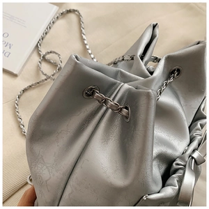 Primer plano del bolso tipo cubo plateado metalizado con textura plisada y detalles de cadena