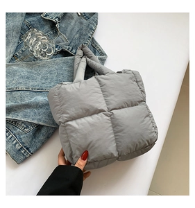 Detail of grey quilted down tote bag featuring large padded square patterns and handles