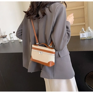 Détail d'un sac bandoulière vintage en toile avec garniture en cuir brun sur un mannequin
