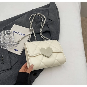 Detail of white quilted handbag with silver heart lock on a grey suit background