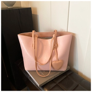 Detailed view of pink pleated leather tote bag with heart charm and metallic buckle