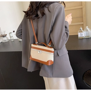 Vue détaillée d'un mini sac en toile avec garniture en cuir brun porté sur un costume gris