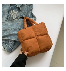 Macro view of orange-brown quilted puffer bag with plush padded texture and carry handle