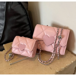 Close-up of pink quilted crossbody bags with heart clasp and metal chain strap