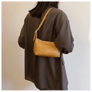Detail of yellow quilted dumpling bag with adjustable strap worn on the shoulder