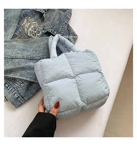 Detail of light blue quilted down tote bag with a soft texture and square stitching