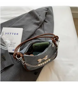Detail of denim handbag interior showing storage capacity for a smartphone and pearl chain