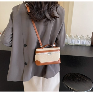 Détail du sac bandoulière vintage en toile porté par un mannequin en blazer gris