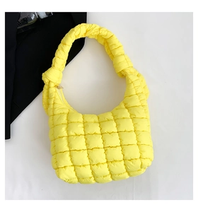 Detalle de un bolso de hombro acolchado amarillo brillante con diseño de asa anudada
