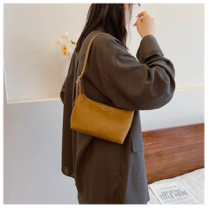 Detail of ginger yellow dumpling bag showing textured faux leather and shoulder strap