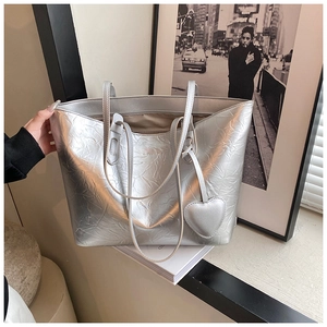Close-up of silver tote bag with metallic crinkled texture and heart-shaped charm