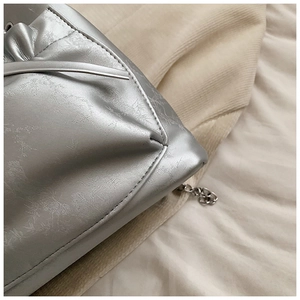 Primer plano del bolso saco plateado metalizado con cuero plisado y detalle de cadena