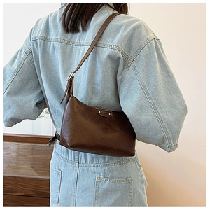 Detail of dark brown faux leather baguette bag with classic quilted stitching patterns