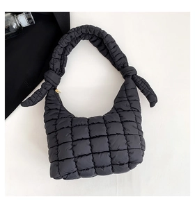 Detalle de bolso acolchado negro con asa de nudo y elegante cremallera metálica dorada