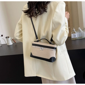 Détail du sac à main en toile beige avec finitions en cuir noir et accents métalliques