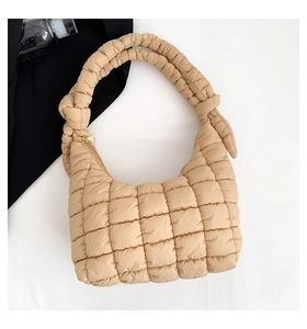 Vista superior detallada de un bolso acolchado beige con textura suave y cremallera metálica