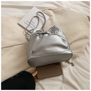 Detalle de bolso cubo plateado con cordón de lazo y correa de cadena metálica