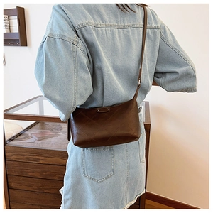 Detail of dark brown quilted dumpling bag with leather texture and slim shoulder strap