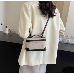 Détail du sac bandoulière en toile beige avec bordure en cuir noir porté par mannequin