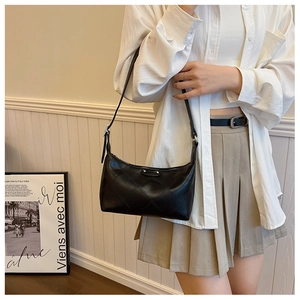 Detail of black quilted dumpling bag on a model featuring fine adjustable leather strap