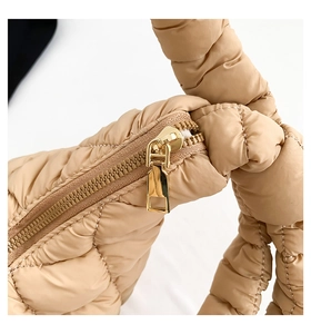 Detail of khaki quilted cotton bag showing golden metal zipper and puffer texture