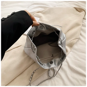 Detalle del interior del bolso de cadena plateado con bolsillo de cremallera y cierre