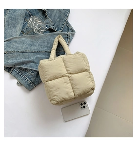 Macro shot of quilted beige tote bag texture with puffer design and denim jacket background