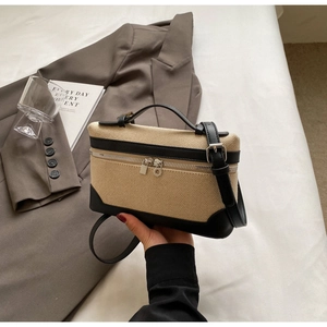 Détail du sac en toile beige avec finitions en cuir noir et fermeture éclair argentée