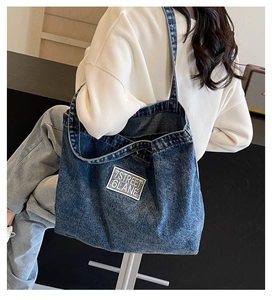 Detail of blue washed denim tote bag showing the 7STREET 6LANE embroidered patch