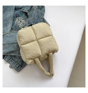 Detailed view of cream quilted puffer bag texture with soft padded handle detail
