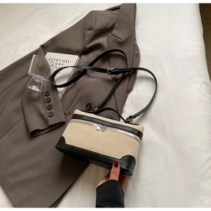 Détail du sac à main en paille tressée avec bordure en cuir noir et poignée dans un décor chic