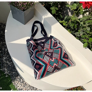 Detail of bohemian knit tote bag with ethnic geometric patterns on a garden display