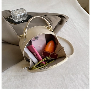 Detailed top view of a cream round crossbody bag showing spacious interior with essentials