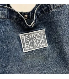 Detail of blue denim tote bag with 7STREET 6LANE patch and metal snap button closure