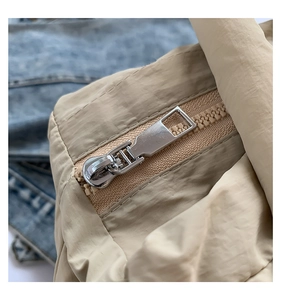 Detailed close-up of smooth silver zipper on a beige quilted puffer bag fabric