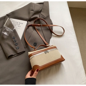 Détail du sac bandoulière vintage en toile et cuir marron sur un lit blanc avec accessoires