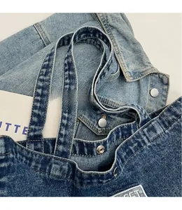 Detailed close-up of dark denim tote bag shoulder strap with silver snap button