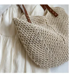 Detail of hand-woven beige crochet shoulder bag with brown leather strap and stitching