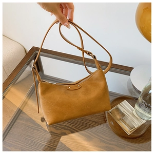 Detail of caramel leather dumpling bag with quilted pattern and adjustable strap
