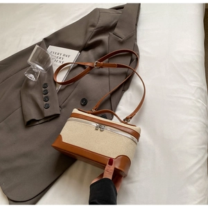 Détail du sac bandoulière en toile et cuir marron avec blazer décontracté et livre