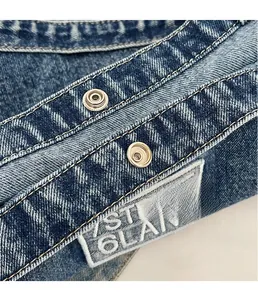 Detailed macro shot of blue denim tote bag with silver metal snaps and precision stitching