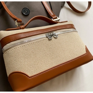 Détail de la toile et du cuir brun avec double fermeture éclair argentée sur le sac bandoulière
