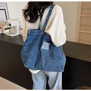 Close-up of blue denim tote bag with 7STREET text worn by model in casual setting